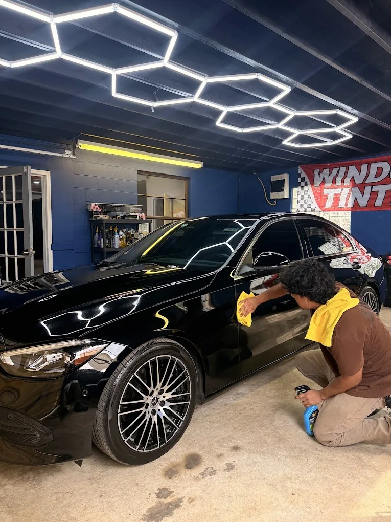 Technician working beside a vehicle inside the Premium Tints & Wraps workshop
